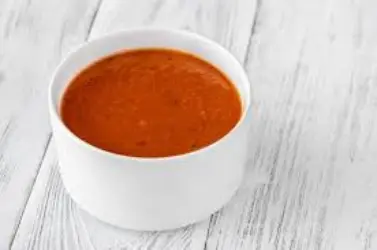 Spicy ghost pepper sauce with bold heat and flavor, served in a small cup